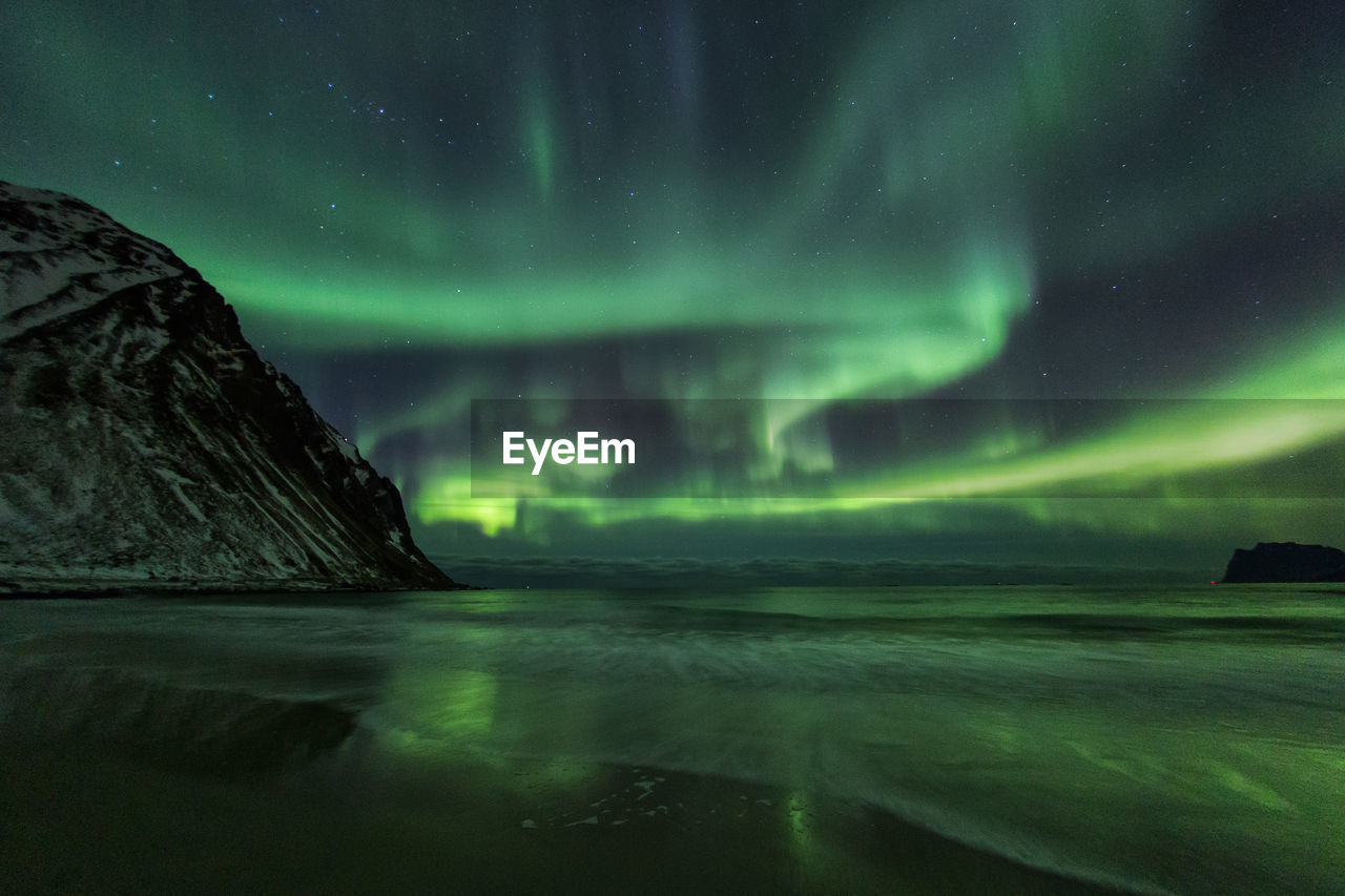 Scenic view of sea against aurora borealis at night