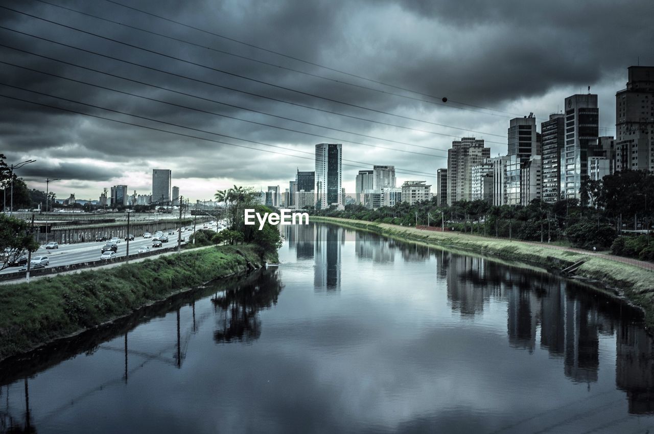 View of city by river against cloudy sky
