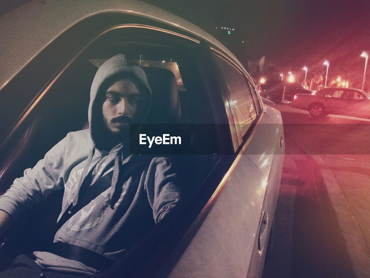 Man looking away while sitting in car at night