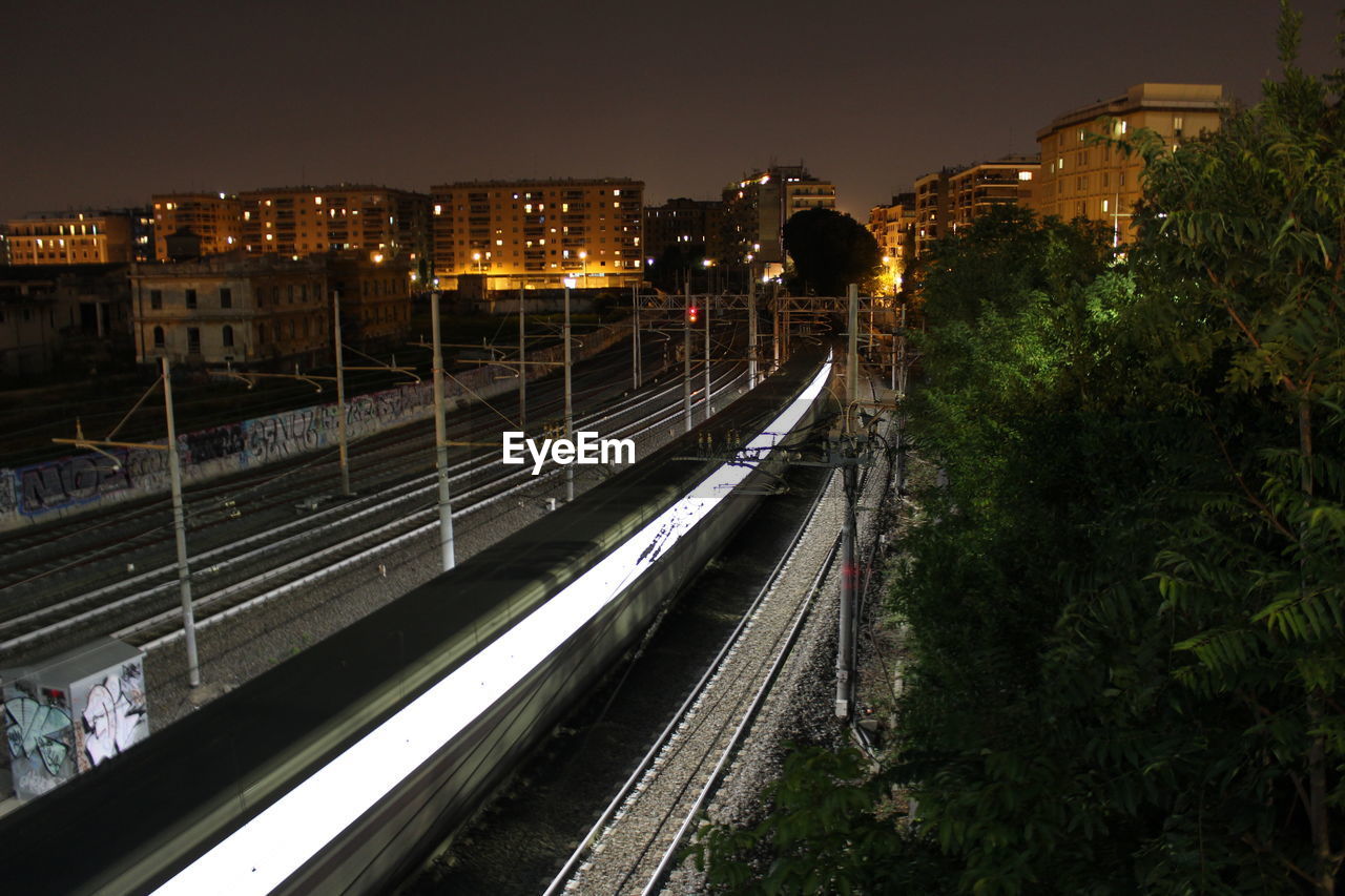 High angle view of train moving on railroad tracks in illuminated city at night