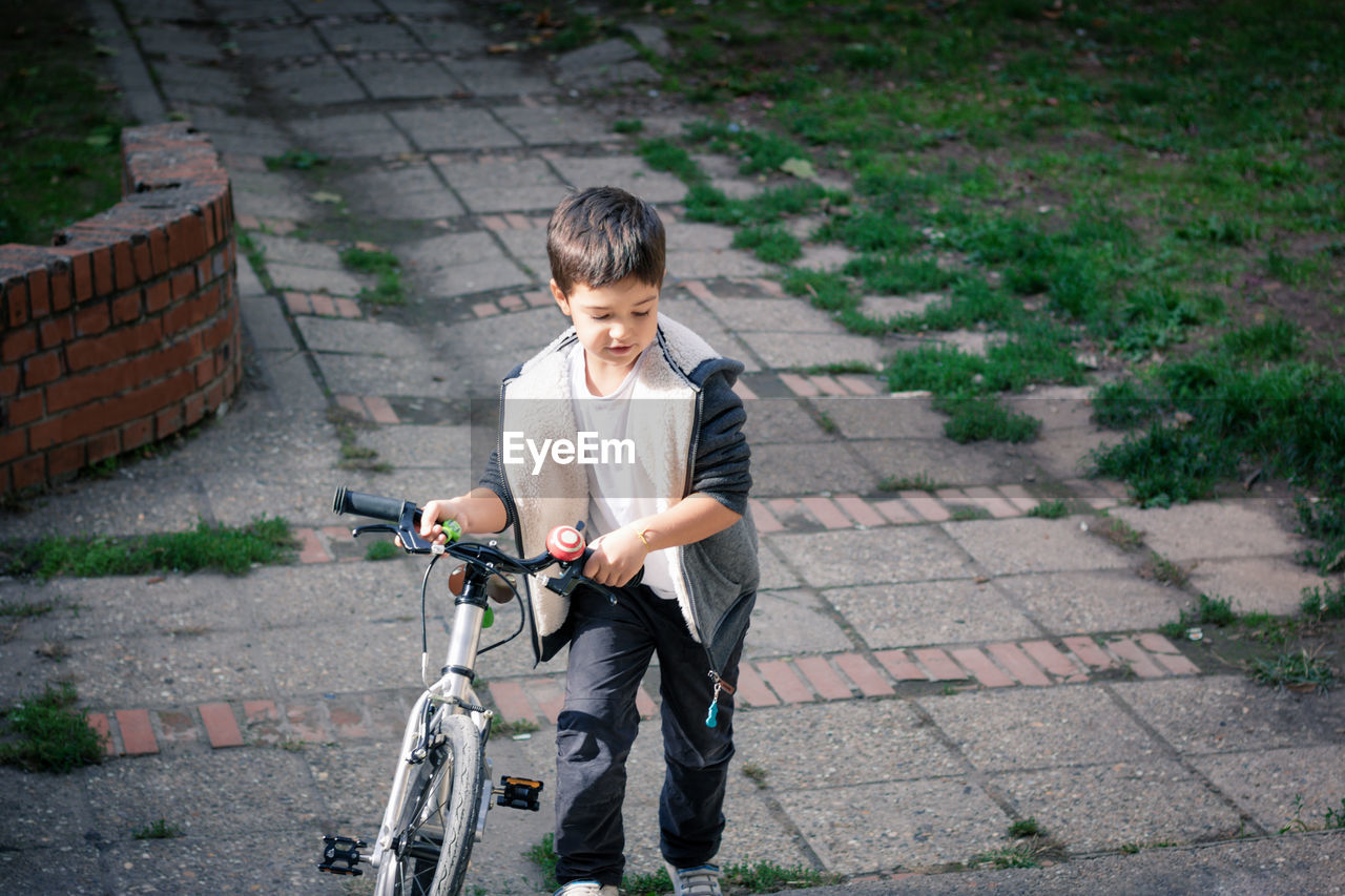Boy walking with bicycle on footpath
