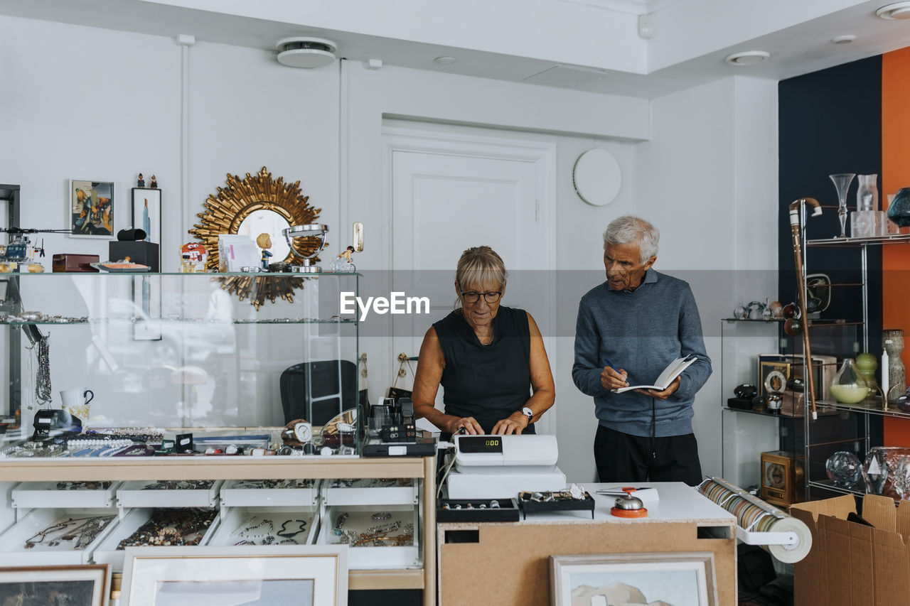 Male and female owners standing at checkout while working in antique shop