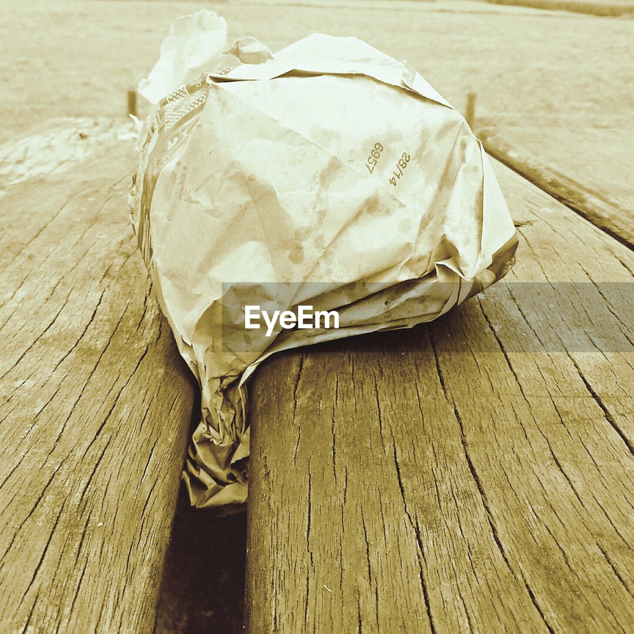 Close-up of paper bag stuck in between wooden planks