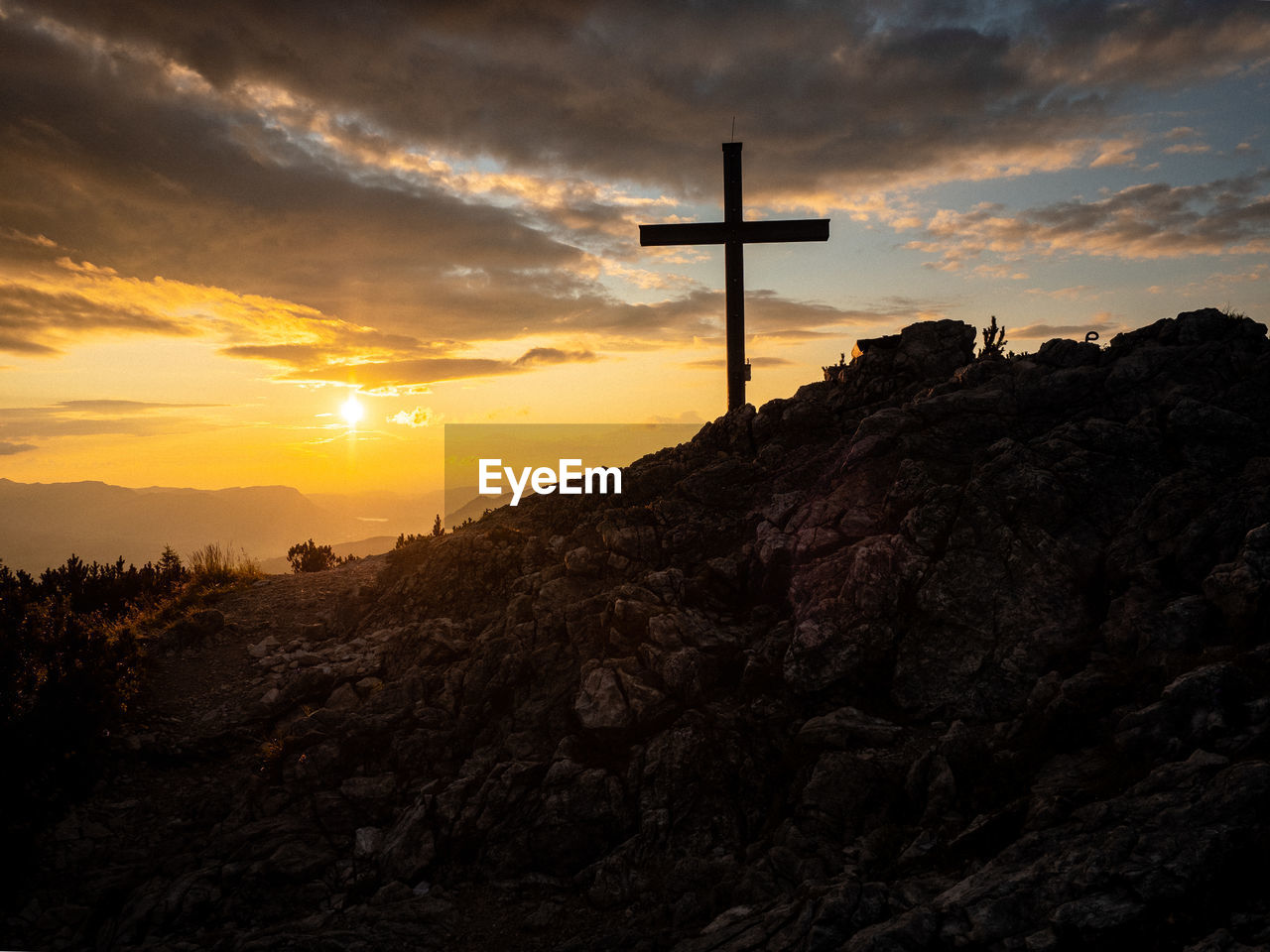 SILHOUETTE CROSS AGAINST MOUNTAINS DURING SUNSET