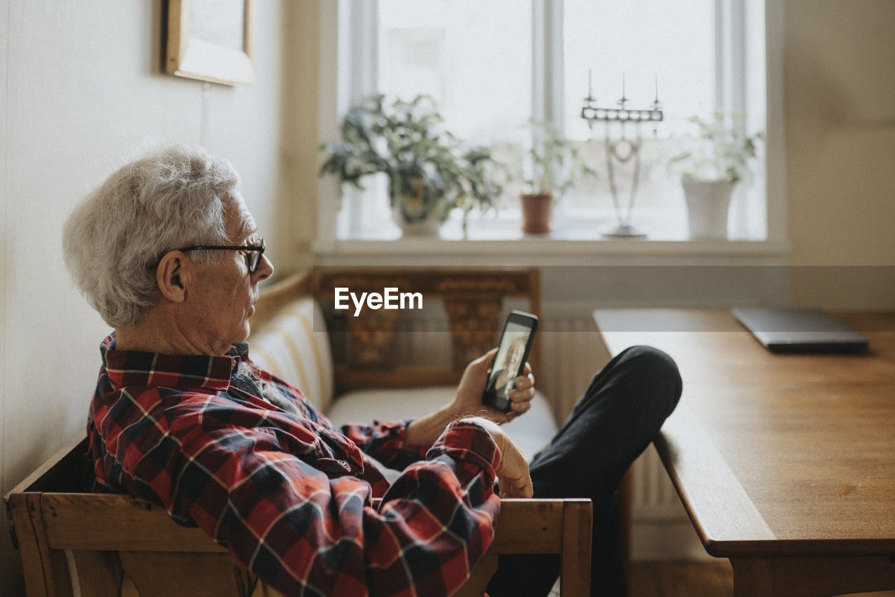 Senior man talking to woman via video call