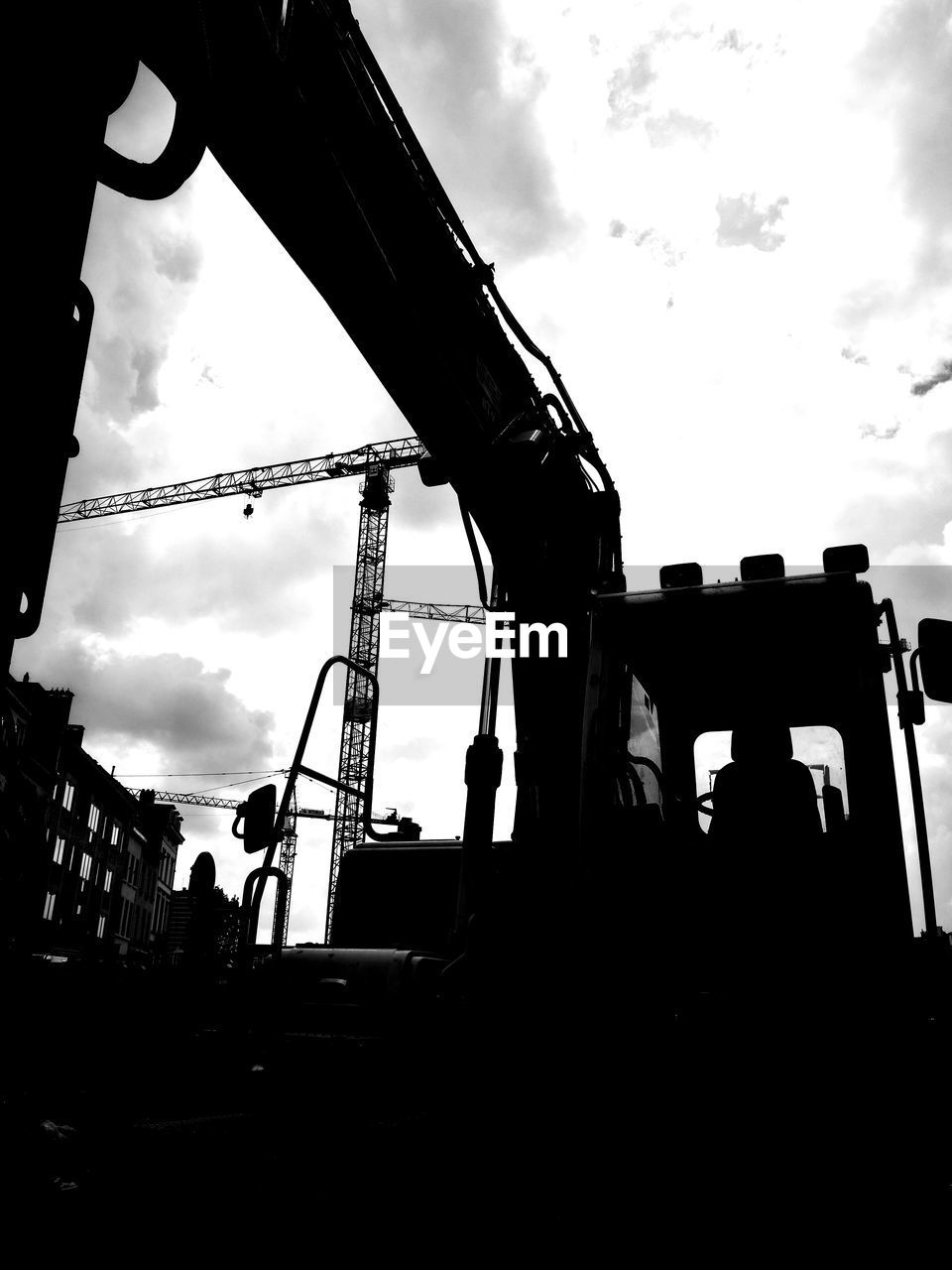 LOW ANGLE VIEW OF SILHOUETTE CRANES AT CONSTRUCTION SITE