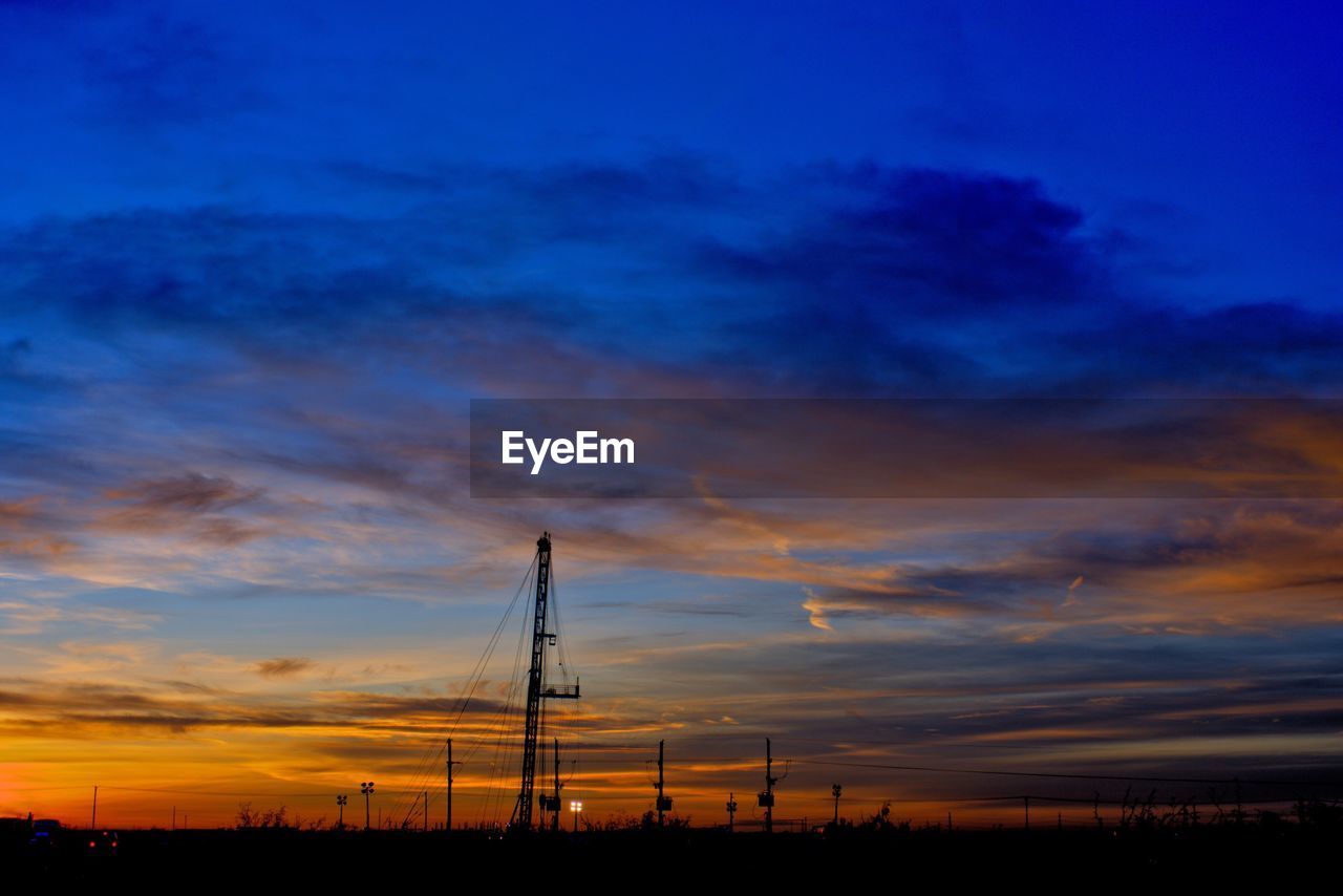 SILHOUETTE OF ELECTRICITY PYLON AGAINST SKY DURING SUNSET