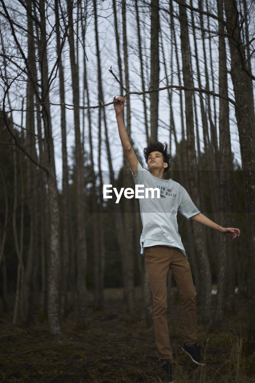 Full length of young woman jumping in forest