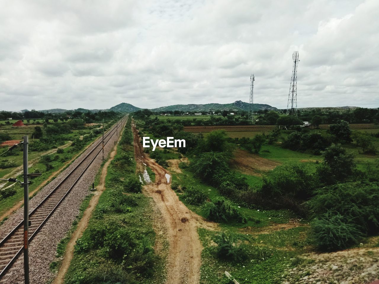 RAILROAD TRACK ON FIELD AGAINST SKY