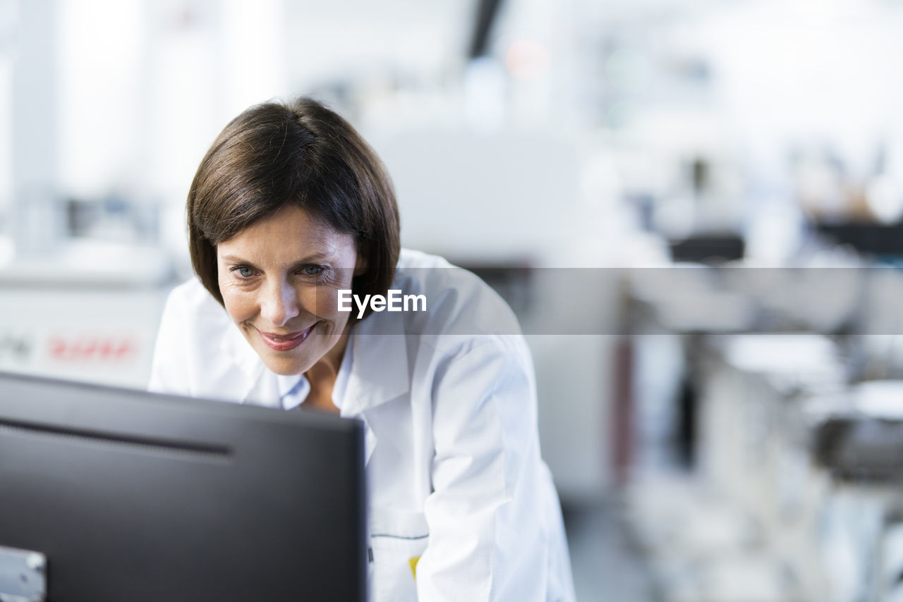 Smiling female engineer using computer at factory
