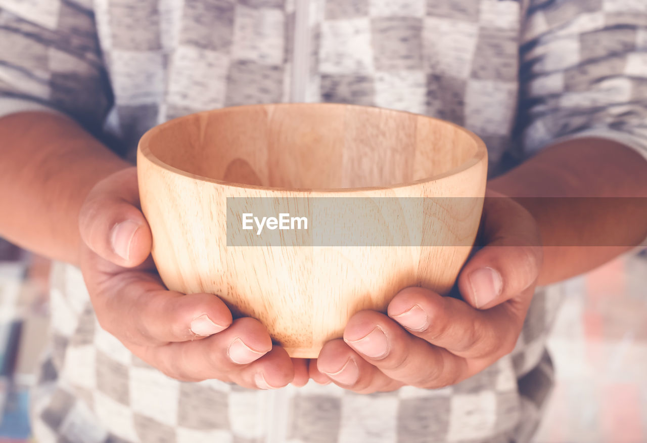 Close-up of man holding wooden bowl