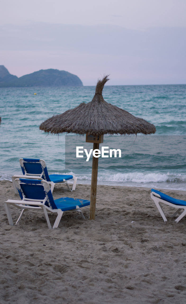 Deck chair on beach against sky