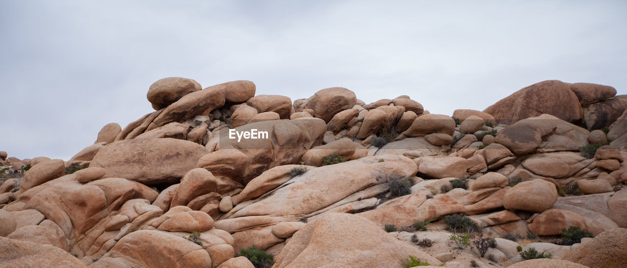 LOW ANGLE VIEW OF ROCKS ON MOUNTAIN AGAINST SKY