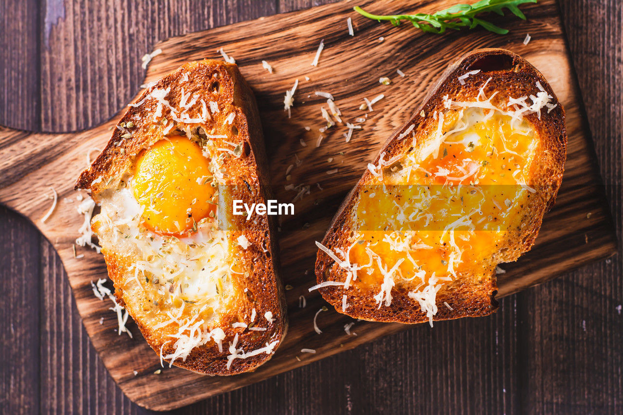 Close up of bread baked with egg and cheese on a cutting board top view