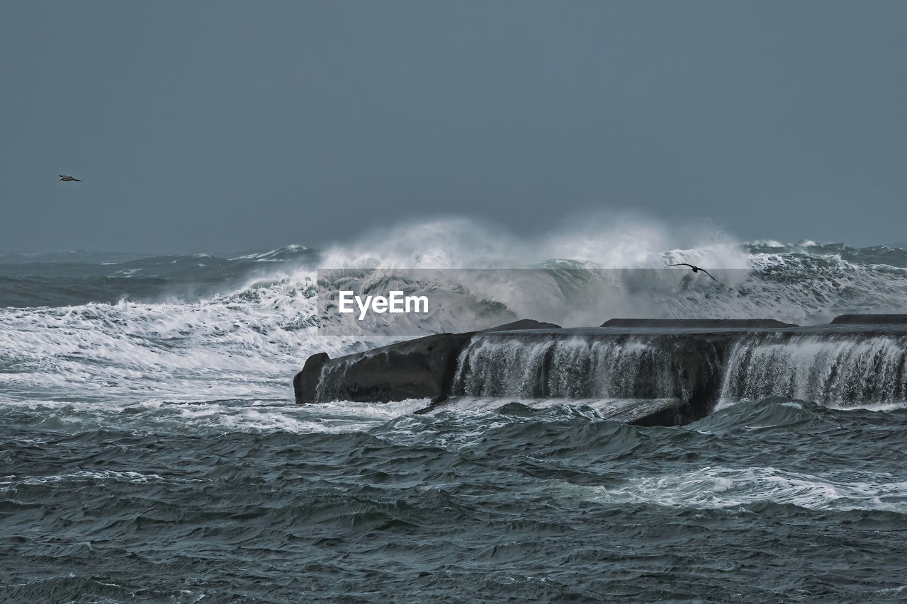 Storm surge creates high waves crashing on a jetty.