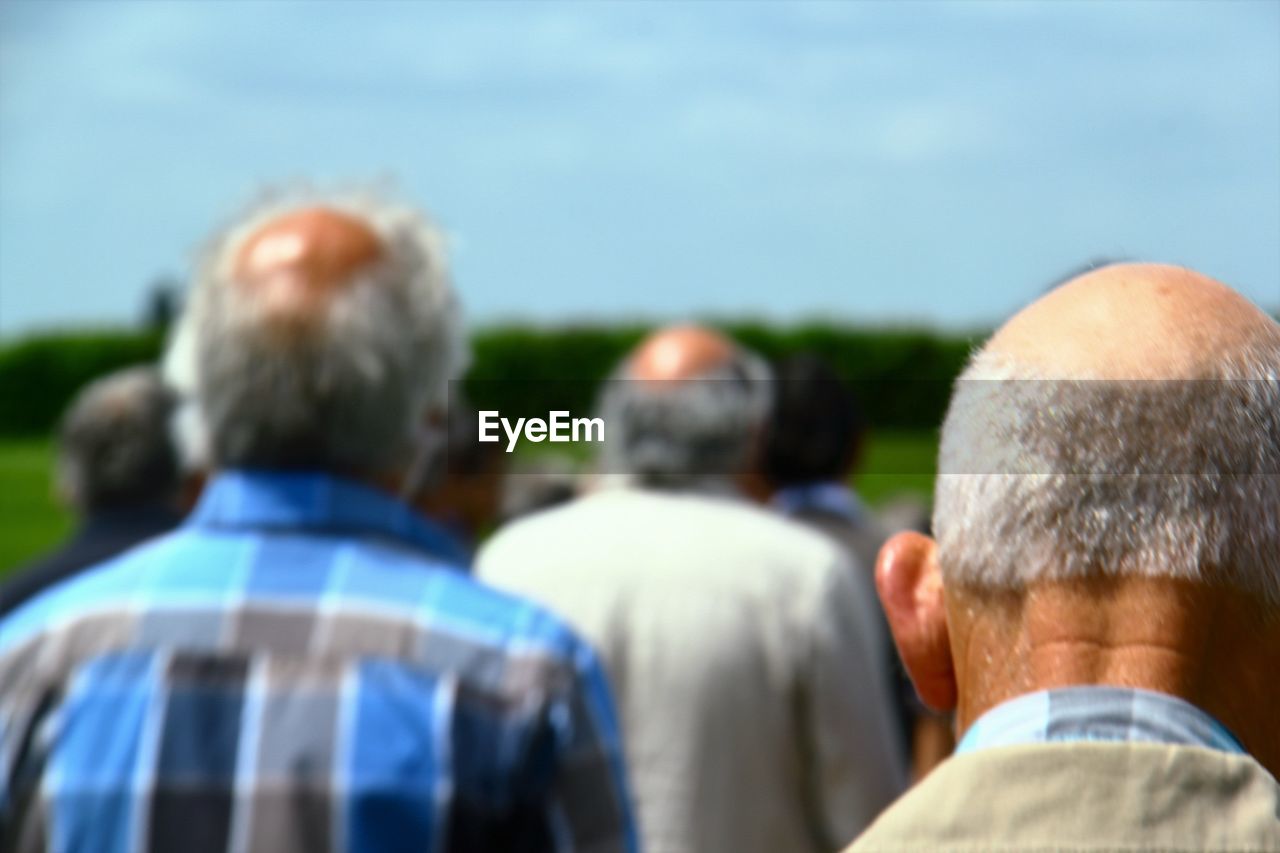 Rear view of men against sky on sunny day