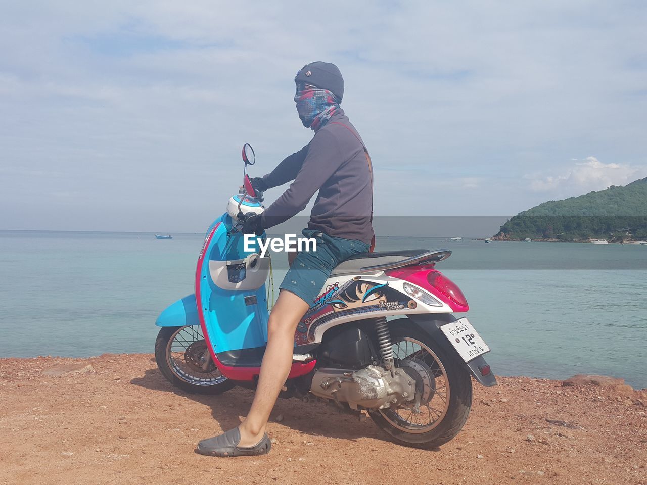 MAN RIDING MOTORCYCLE AGAINST SEA
