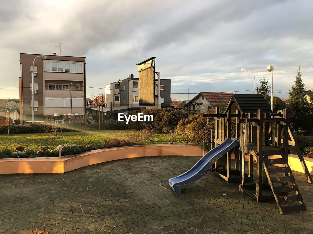 View of playground by buildings against sky during sunrise