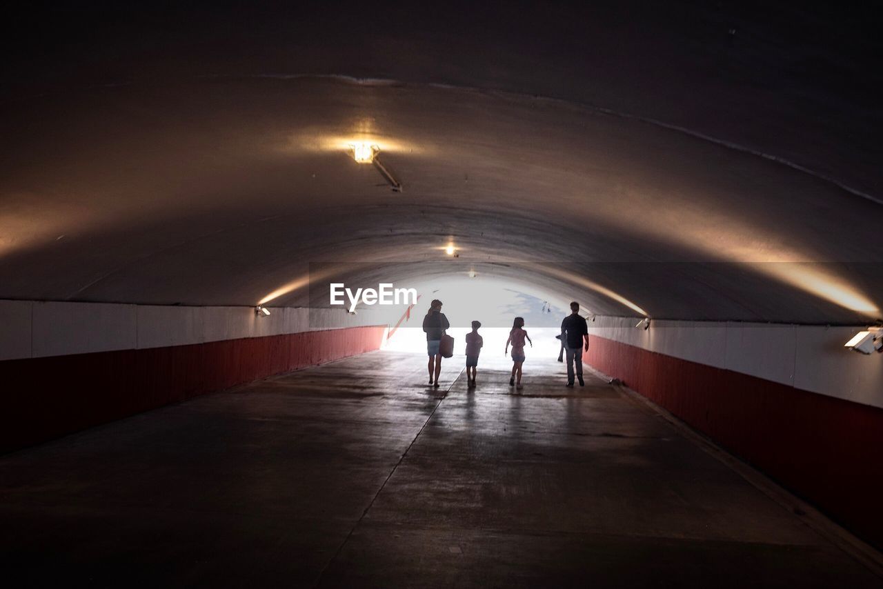 Rear view of people walking in tunnel