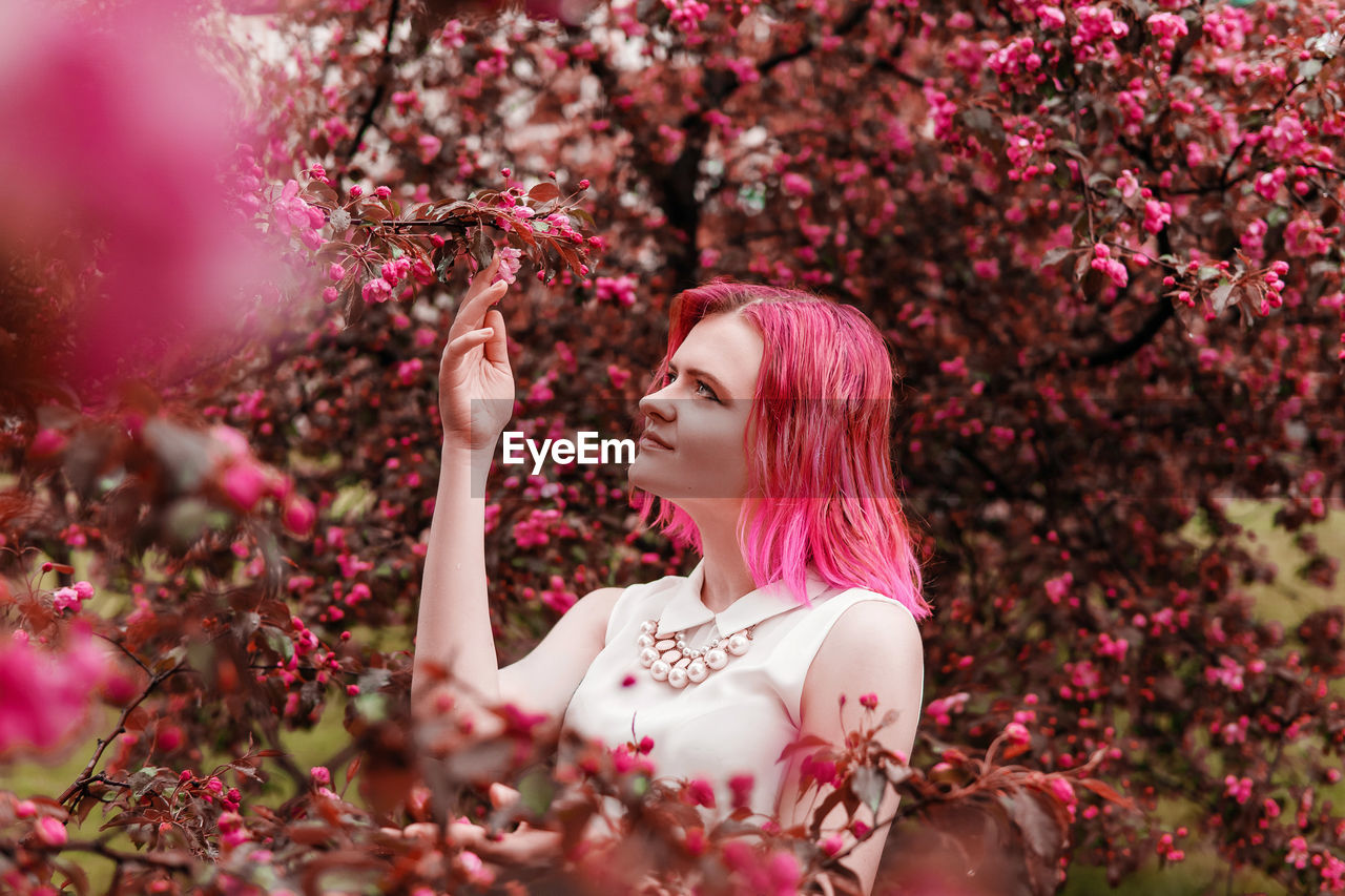 Young girl with pink hair in apple orchard.