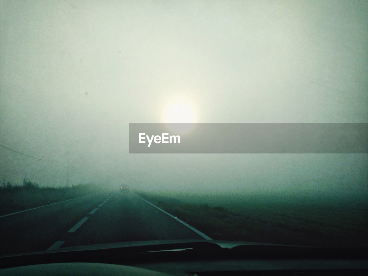 Cropped image of car on country road against sky during foggy weather