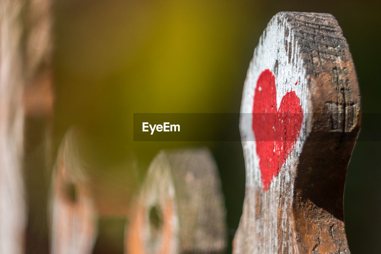 CLOSE-UP OF HEART SHAPE DECORATION ON WOOD AGAINST BLURRED BACKGROUND