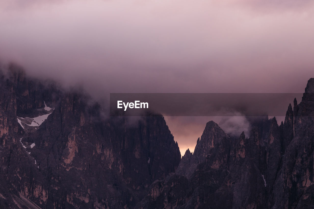 Panoramic view of mountains against sky with storm clouds during sunset