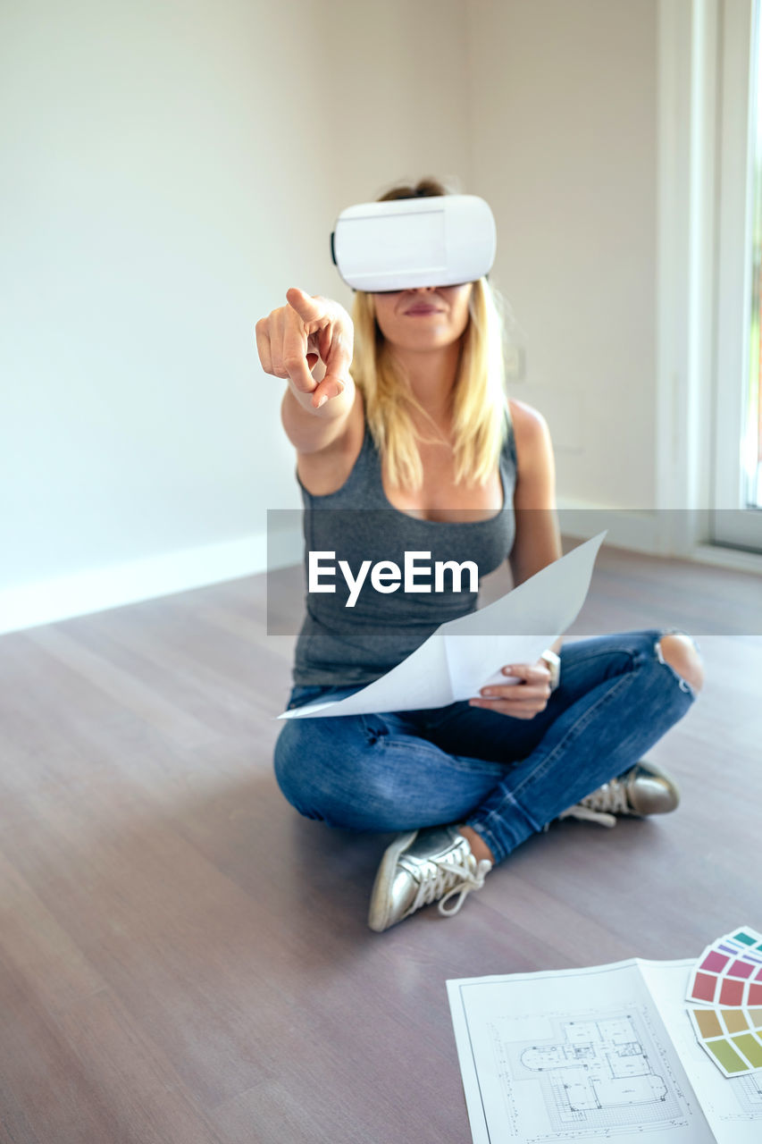 Woman wearing virtual reality simulator while sitting at home
