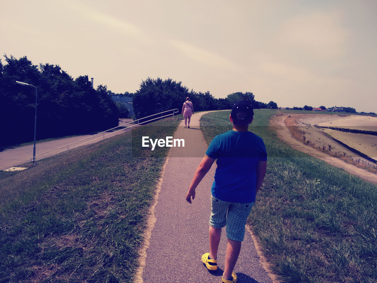 Rear view of man and woman walking on pathway against sky