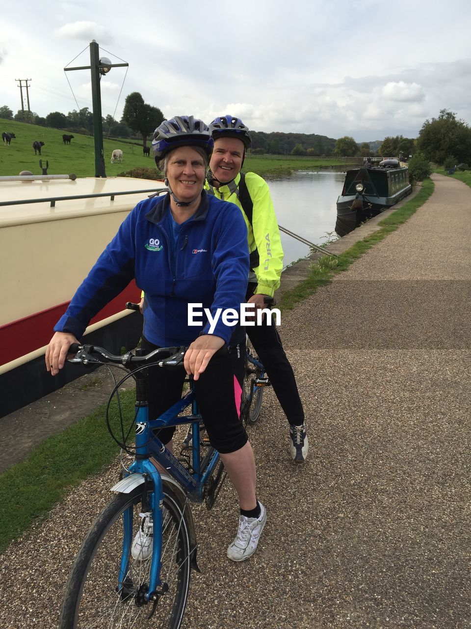 Portrait of smiling couple riding tandem bicycle by canal