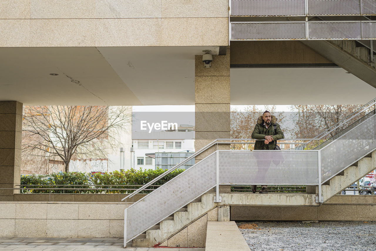 Bearded hipster man relaxing on stairs in a building complex