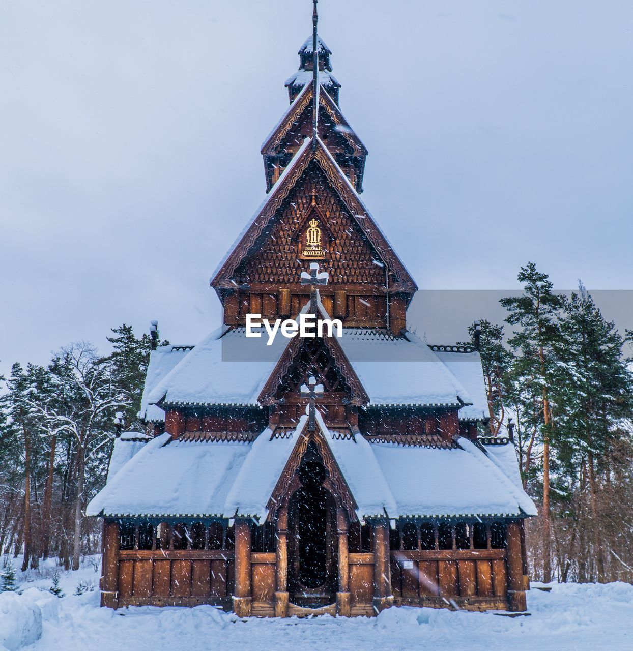 Old church structure by trees against sky during winter