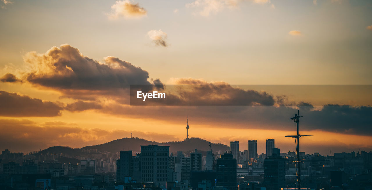 Buildings in city against cloudy sky