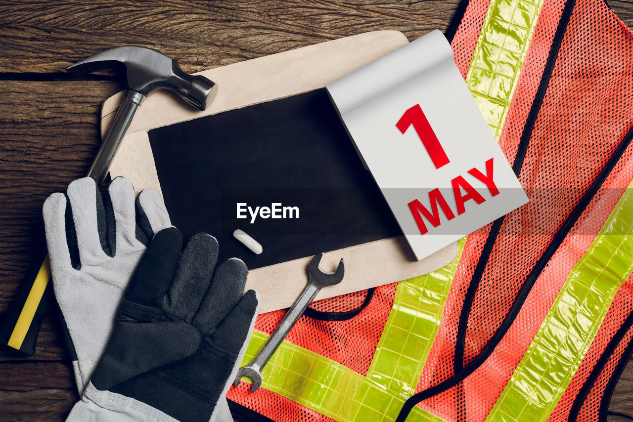 Directly above shot of reflective clothing and protective glove with calendar and work tool on table