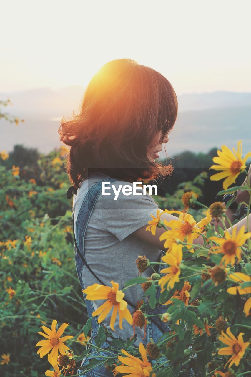 Side view of woman standing by flowers