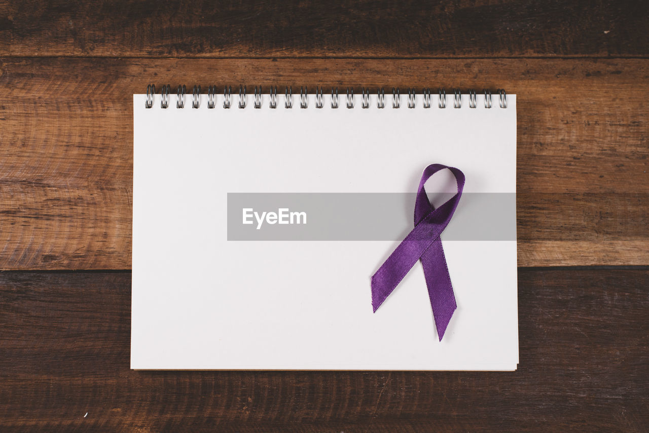 Purple ribbon on a blank notebook for copy space. concept of epilepsy and alzheimer awareness