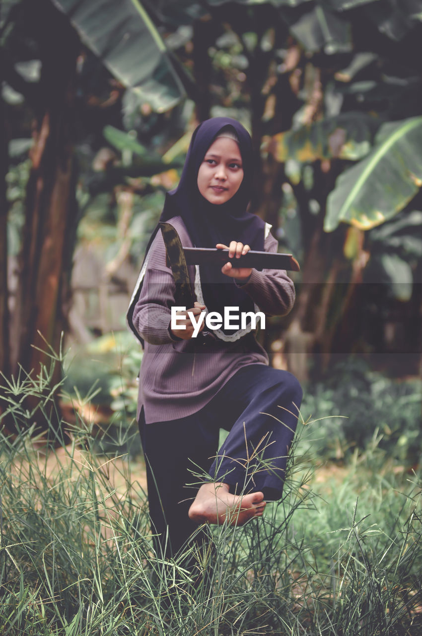 Portrait of young woman standing against plants