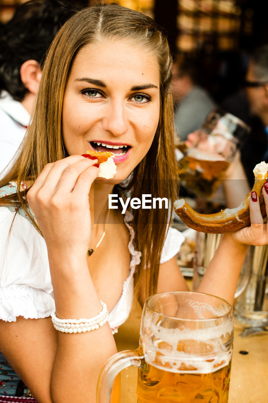 Portrait of young woman having pretzel during oktoberfest