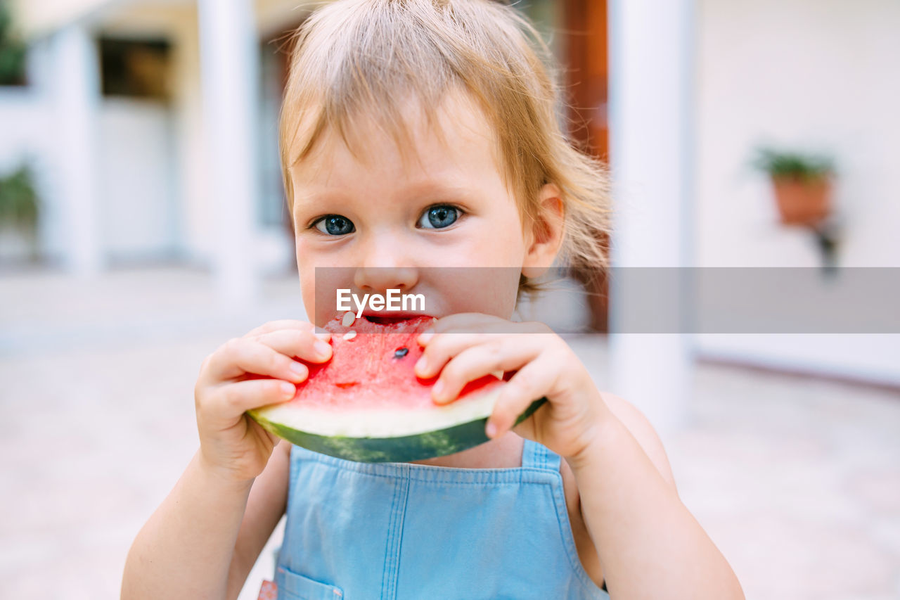 Portrait of cute girl eating slice of watermelon