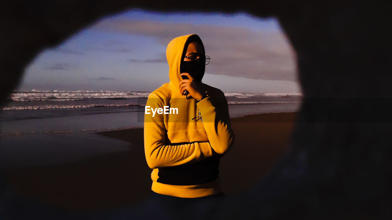 Young boy standing on beach against sky