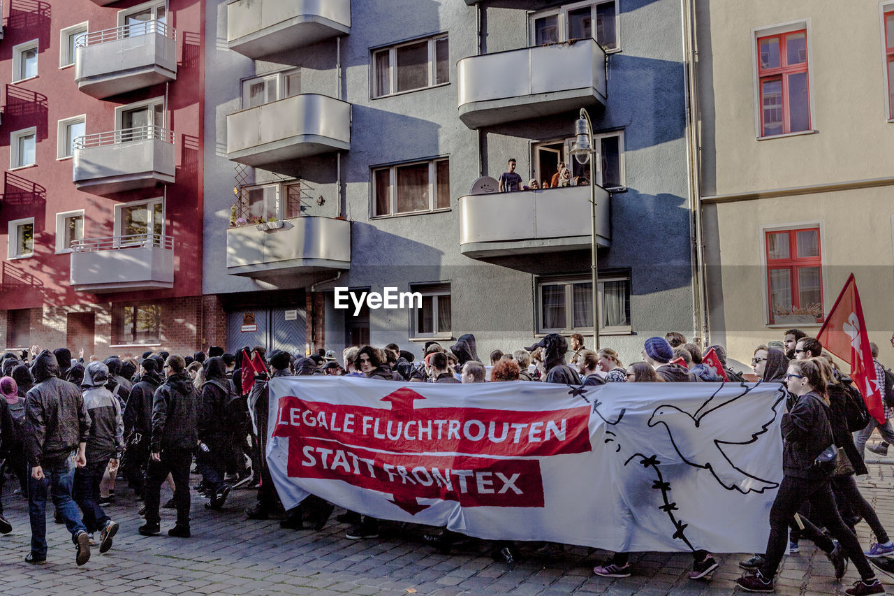 Crowd walking on street by buildings at may day