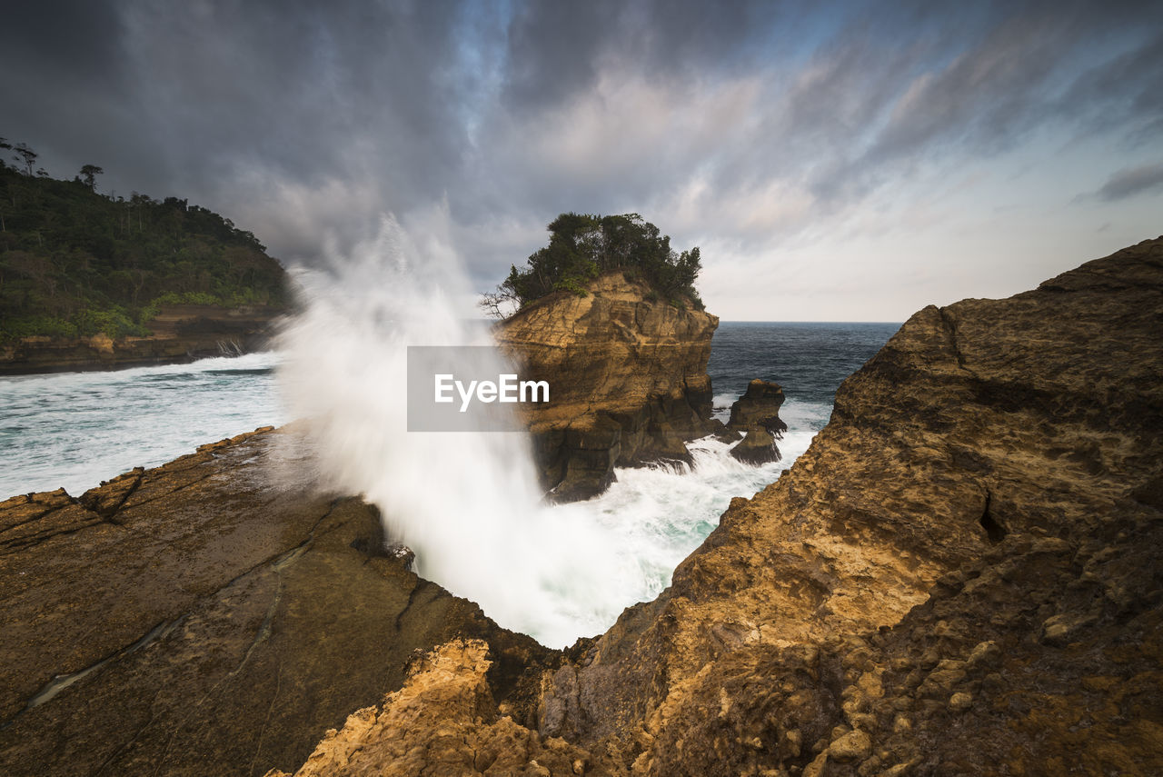 Scenic view of rocks on shore against sky