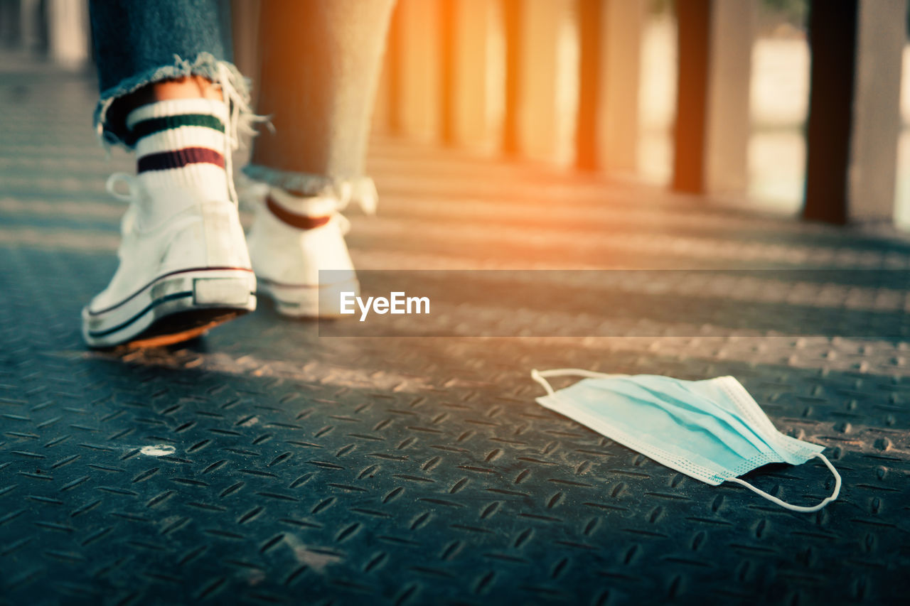 LOW SECTION OF WOMAN STANDING ON FLOORING