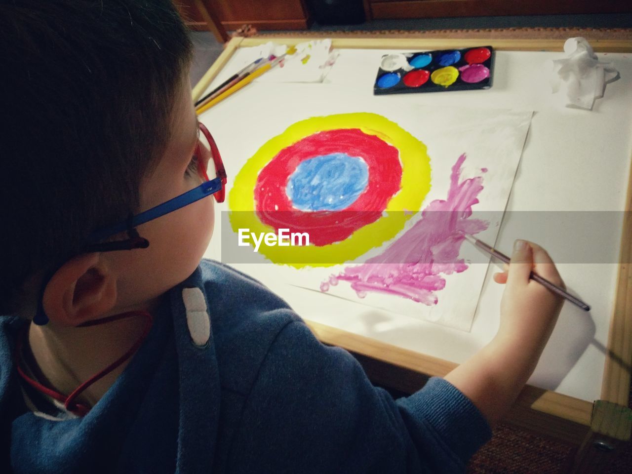 High angle view of boy painting on paper at home