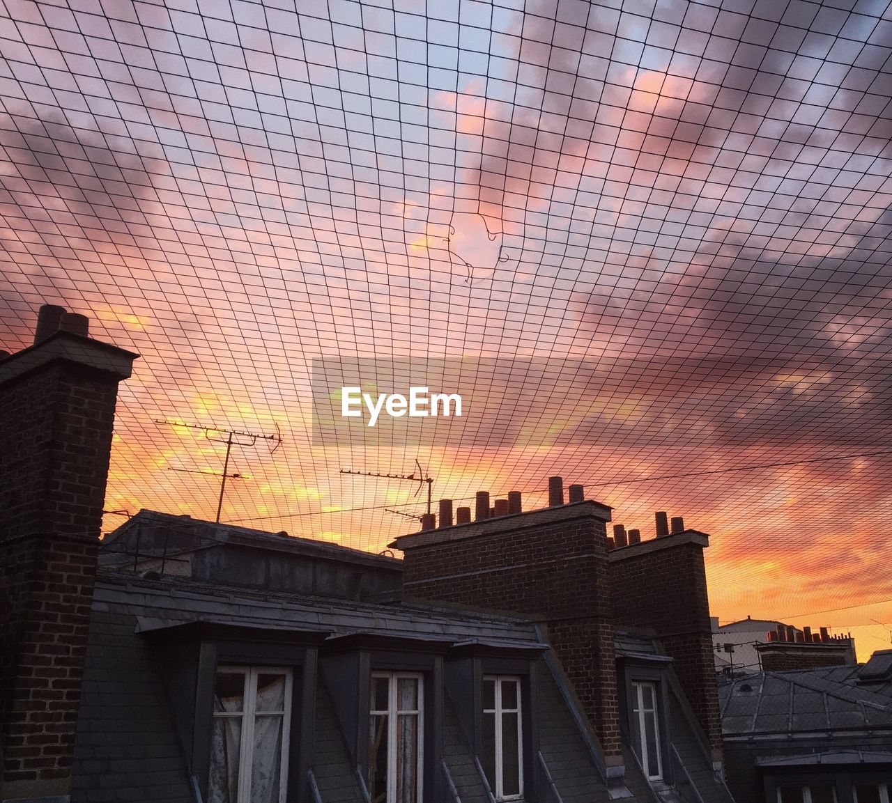 Low angle view of netting over house against sky during sunset