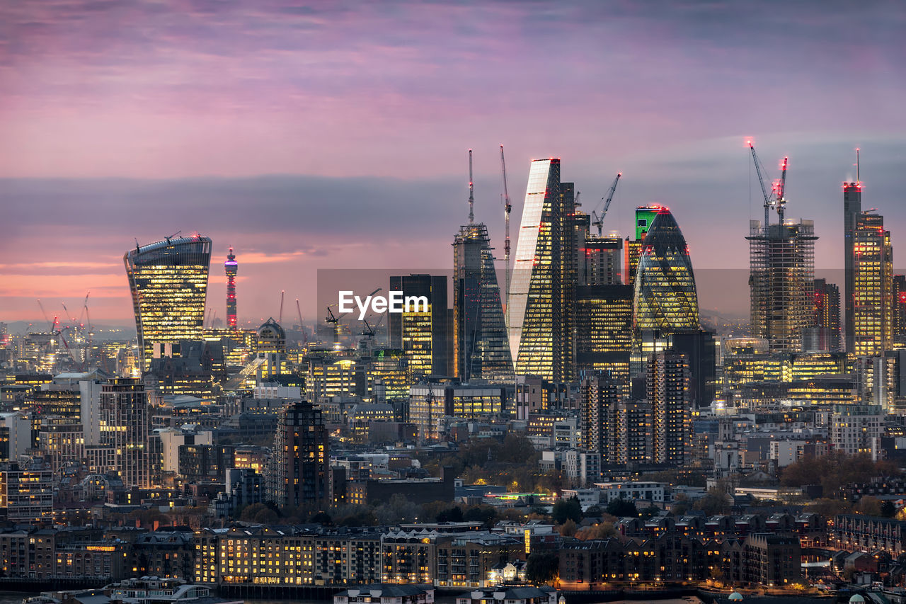 Illuminated buildings in city at sunset