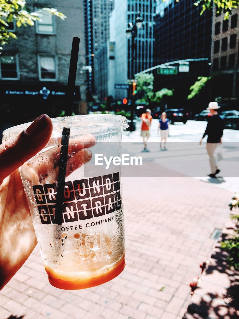 CLOSE-UP OF A HAND HOLDING DRINK WITH BEER IN CITY