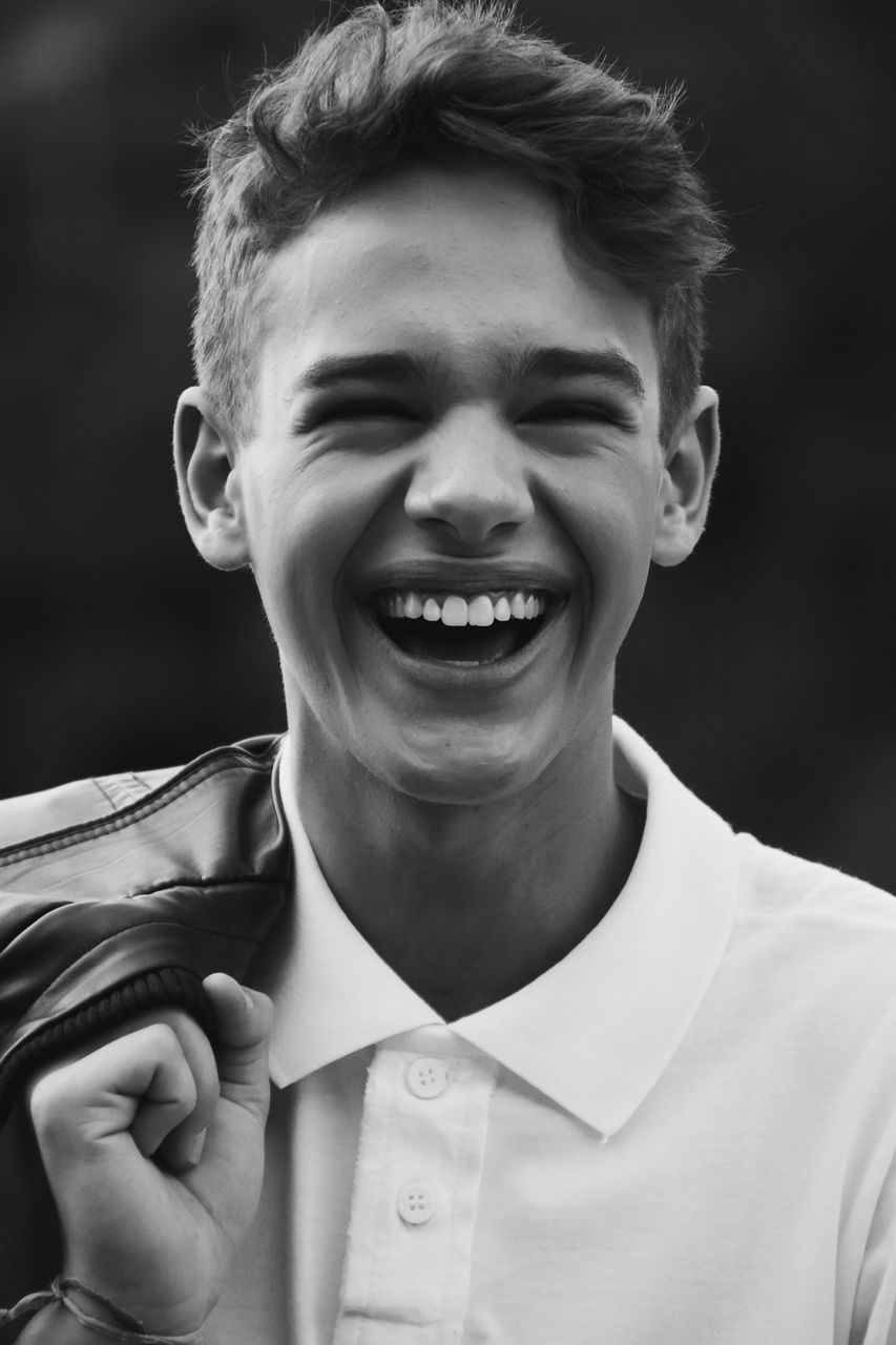 Cheerful teenage boy with jacket at park