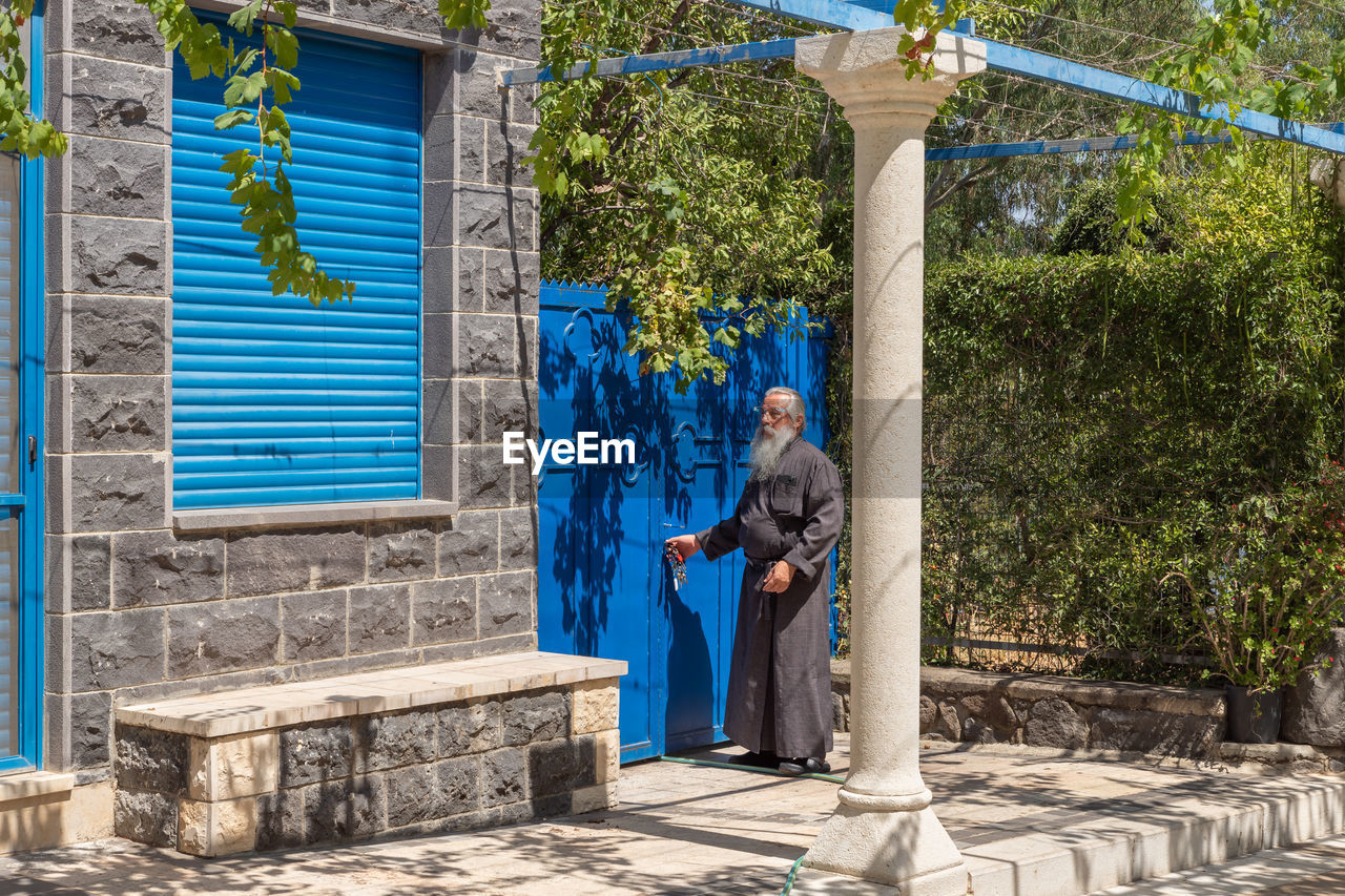 MAN STANDING AGAINST BLUE WALL