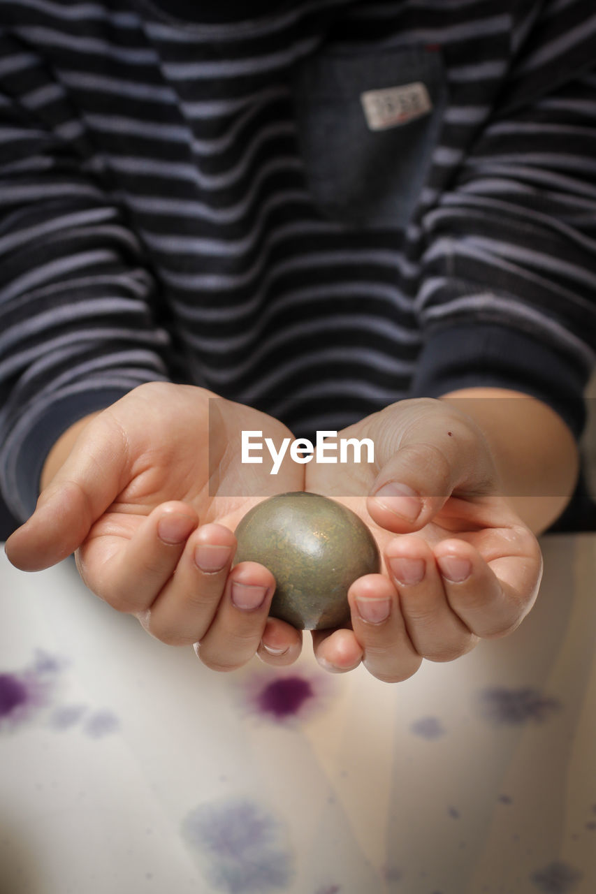 Midsection of person holding easter egg at table